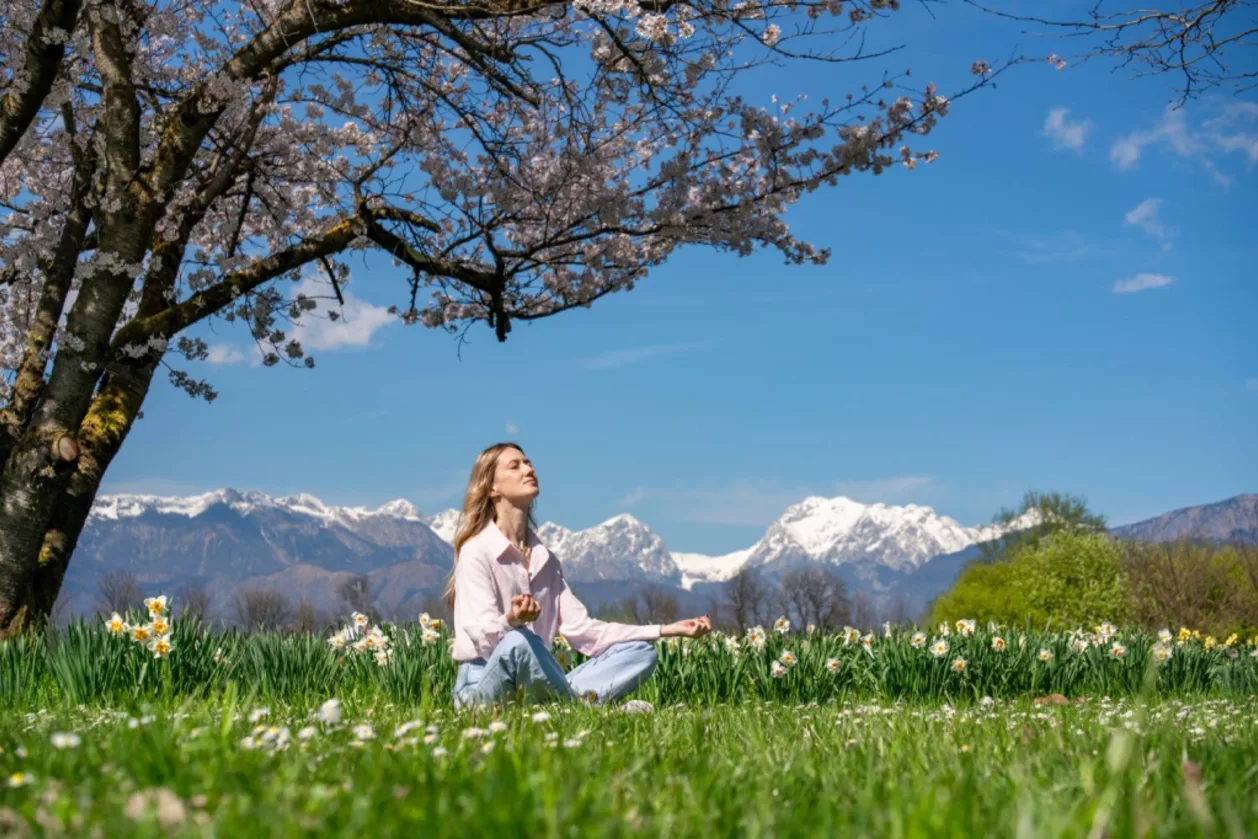 Woman meditating under blooming cherry tree